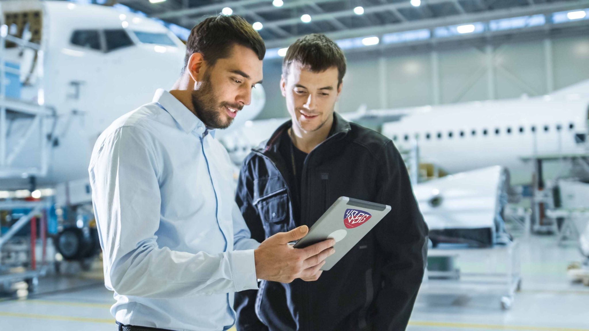 4SSG UK Ltd Aircraft Maintenance Worker and Engineer having Conversation. Holding Tablet.